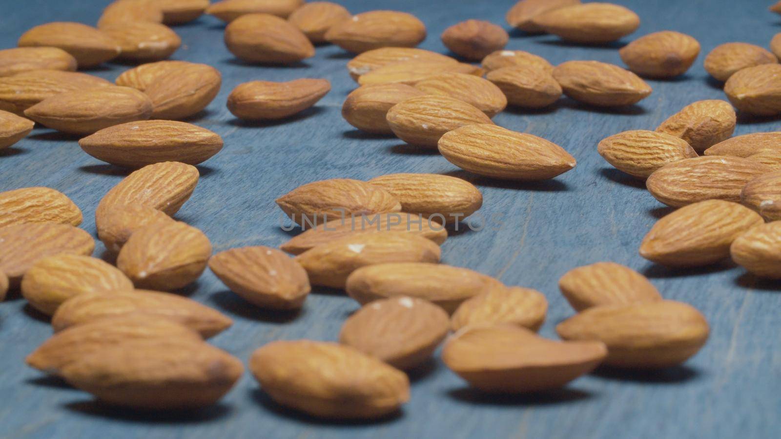 Extreme close up almond nuts on blue background. Product rich in minerals and vitamins. Macro shooting