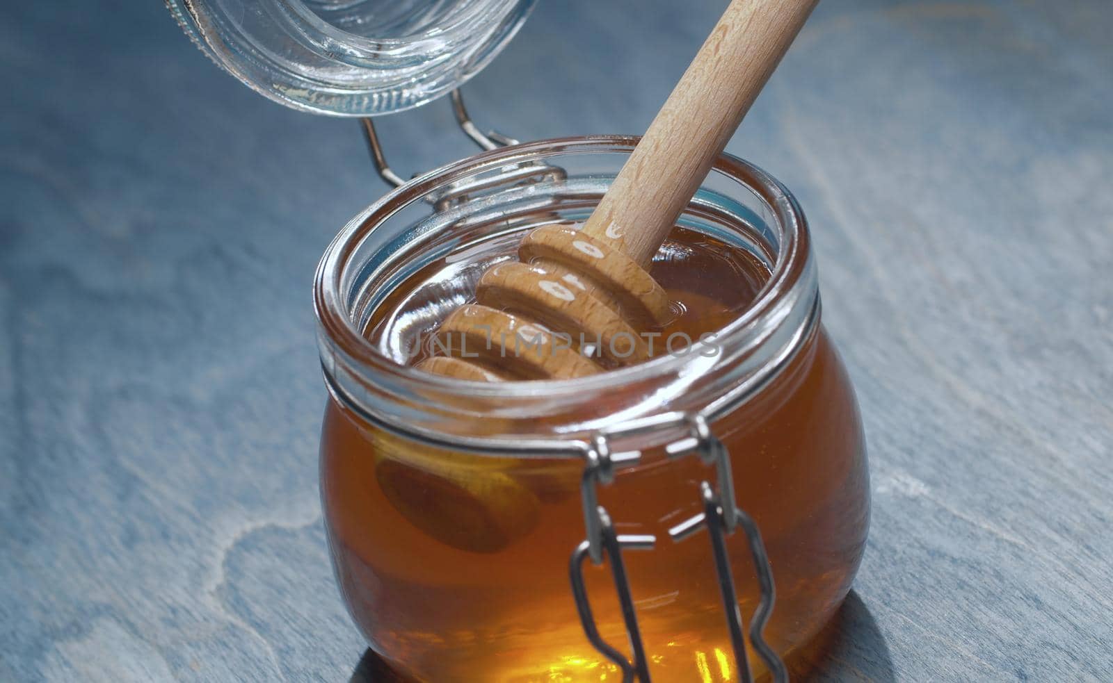 Close up fresh honey in glass jar on blue background. Healthy fresh food concept. High angle view