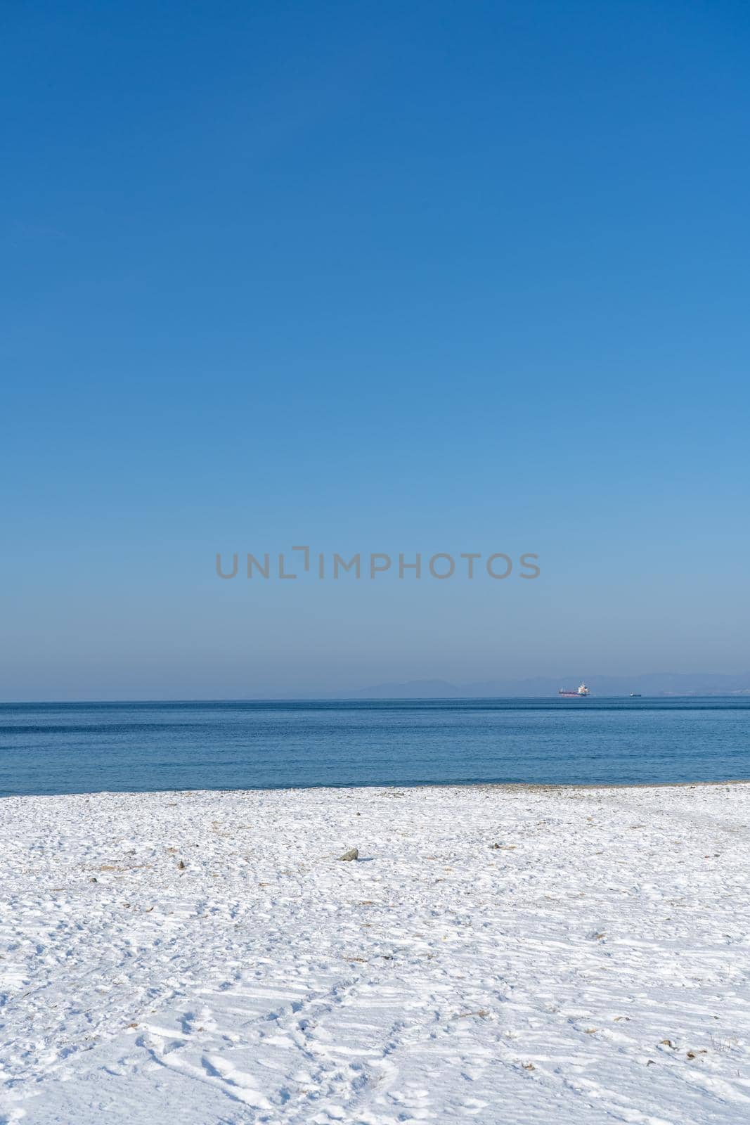 Seascape with a beach in snow and bright sun