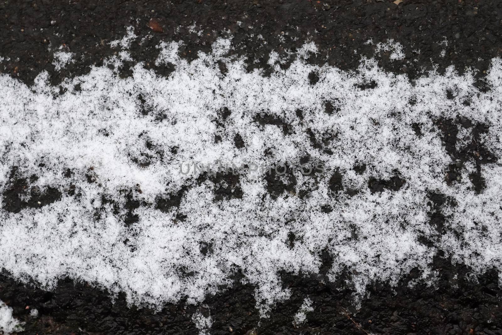 Dirty tracks of snow on asphalt on a small german road.