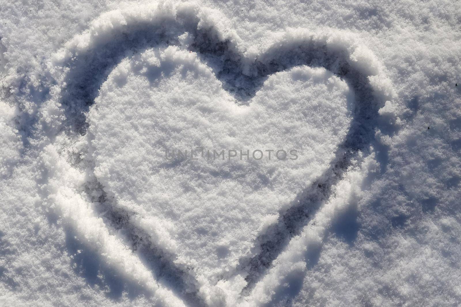 Sunny fresh snow texture with drawn valentine heart symbol.