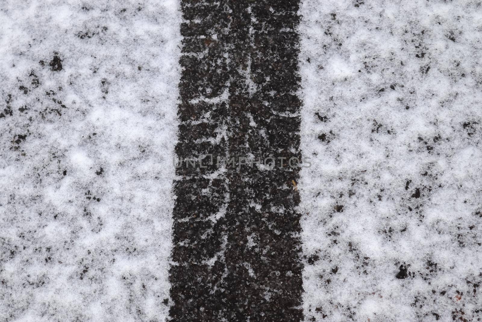 Dirty tracks of snow on asphalt on a small german road.