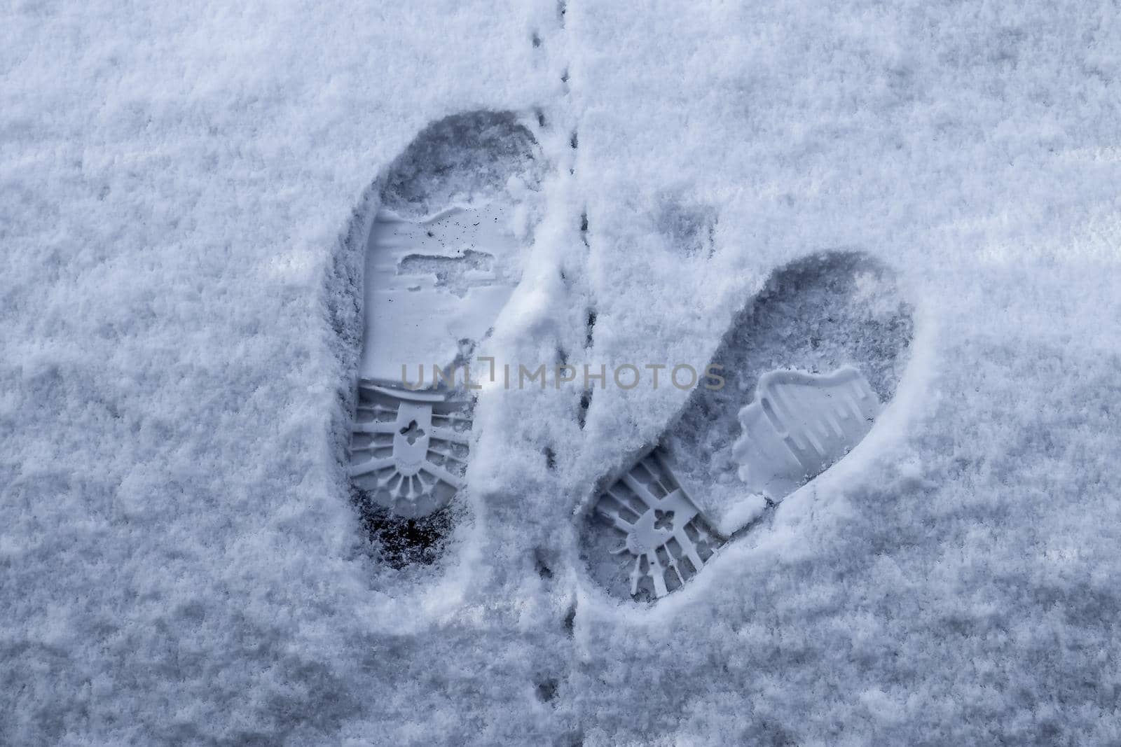 Footsteps of male shoes in fresh white snow in winter.