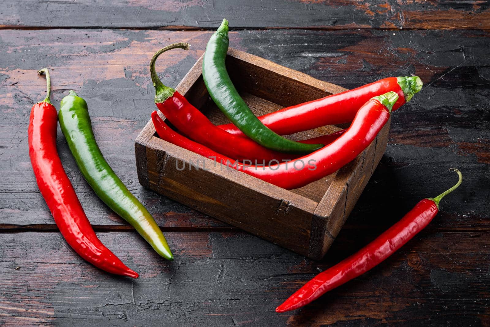 Red and green chili pepper set, in wooden box, on dark wooden background