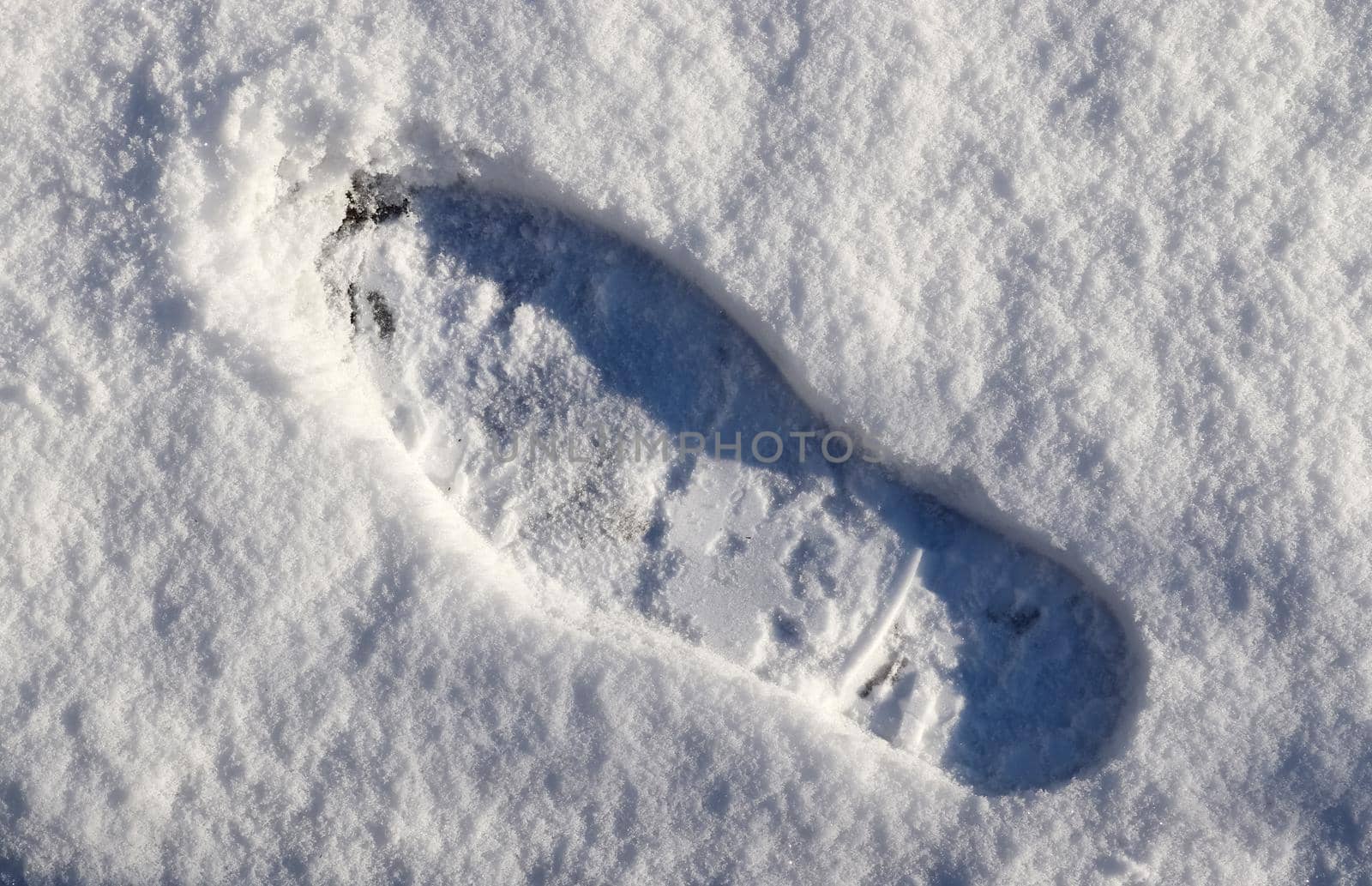 Footsteps of male shoes in fresh white snow in winter.