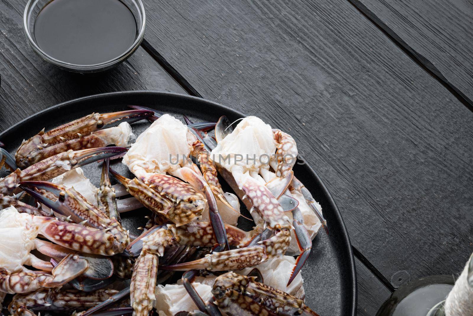 Fresh raw Blue Swimming Crab ocean gourme parts set, on plate, on black wooden table background , with copyspace and space for text