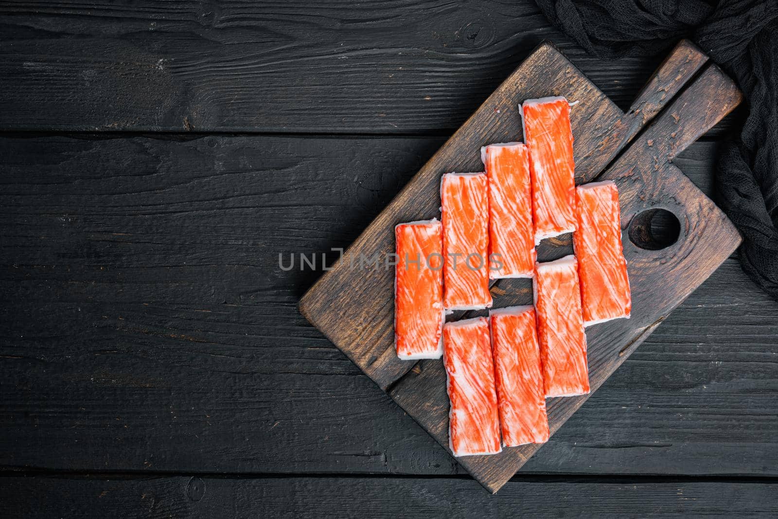 Fresh Crab meat stick surimi with blue swimming crab set, on wooden cutting board, on black wooden table background, top view flat lay , with copyspace and space for text