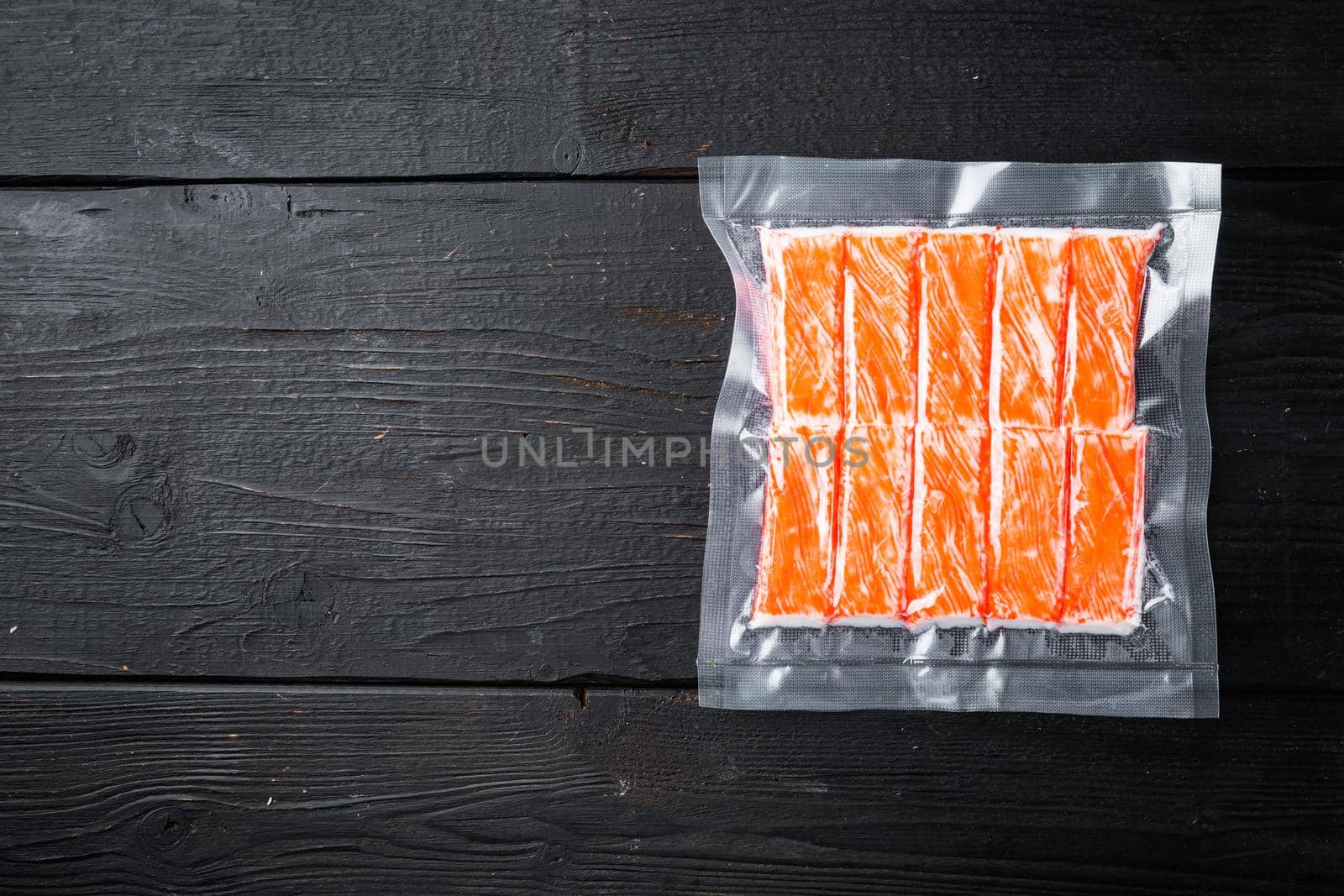 Crab stick surimi vacuum pack set, on black wooden table background, top view flat lay , with copyspace and space for text