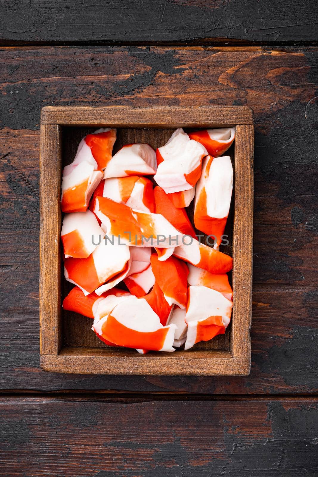 Fresh Crab meat stick surimi set, in wooden box, on dark wooden background, top view flat lay