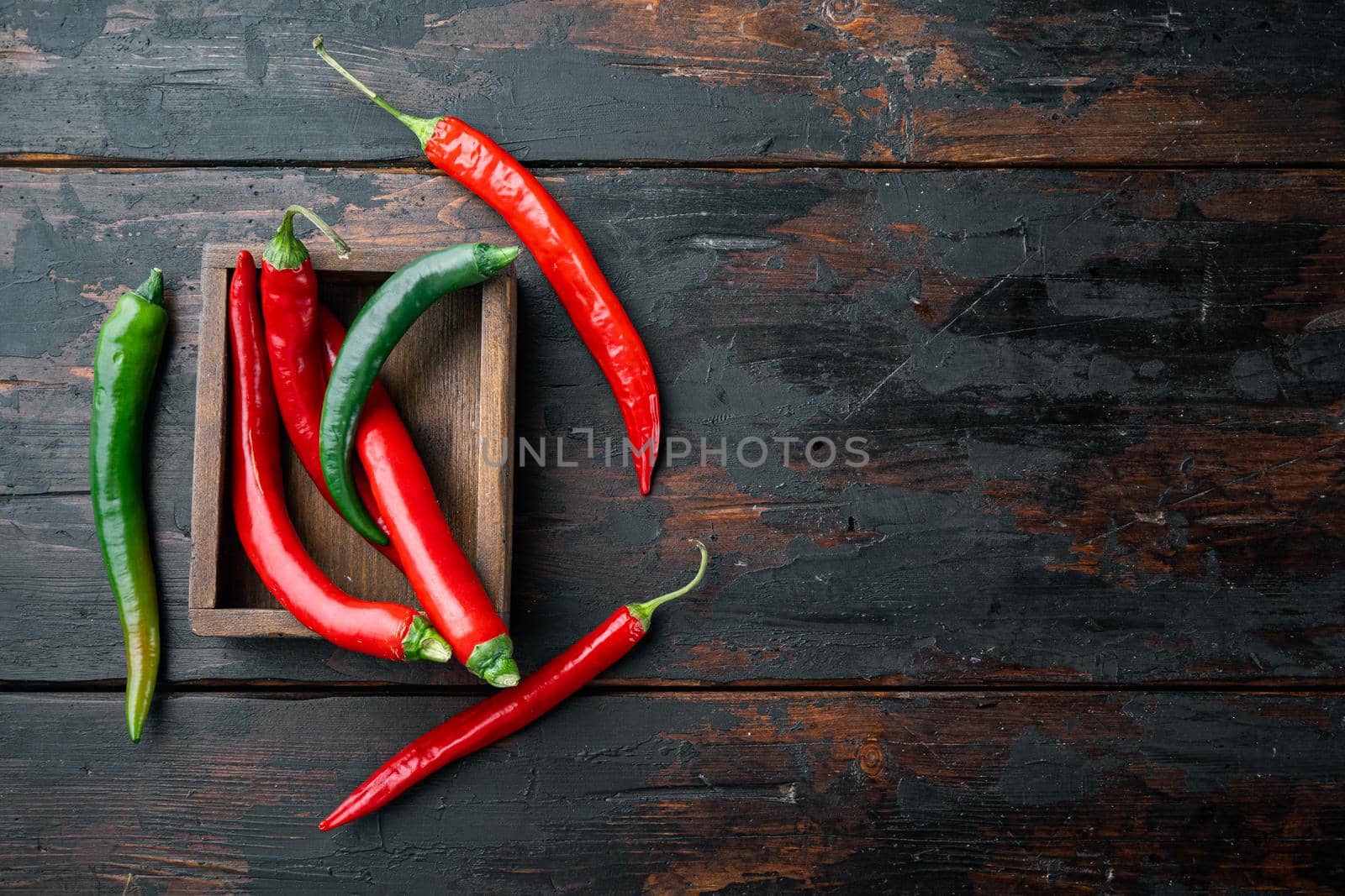 Red and green chili pepper set, in wooden box, on dark wooden background, top view flat lay , with copyspace and space for text