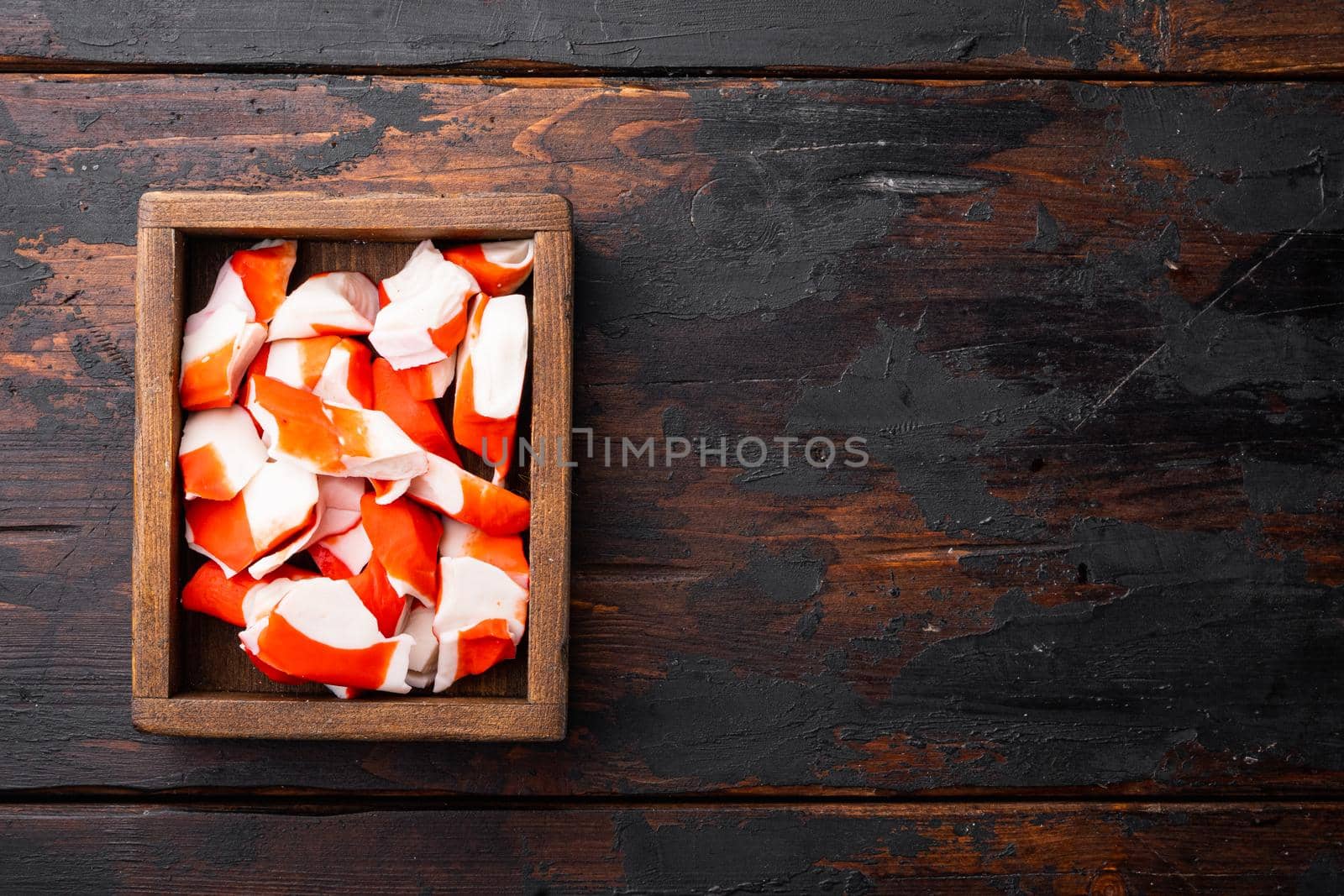 Asian snack surimi set, in wooden box, on dark wooden background, top view flat lay , with copyspace and space for text