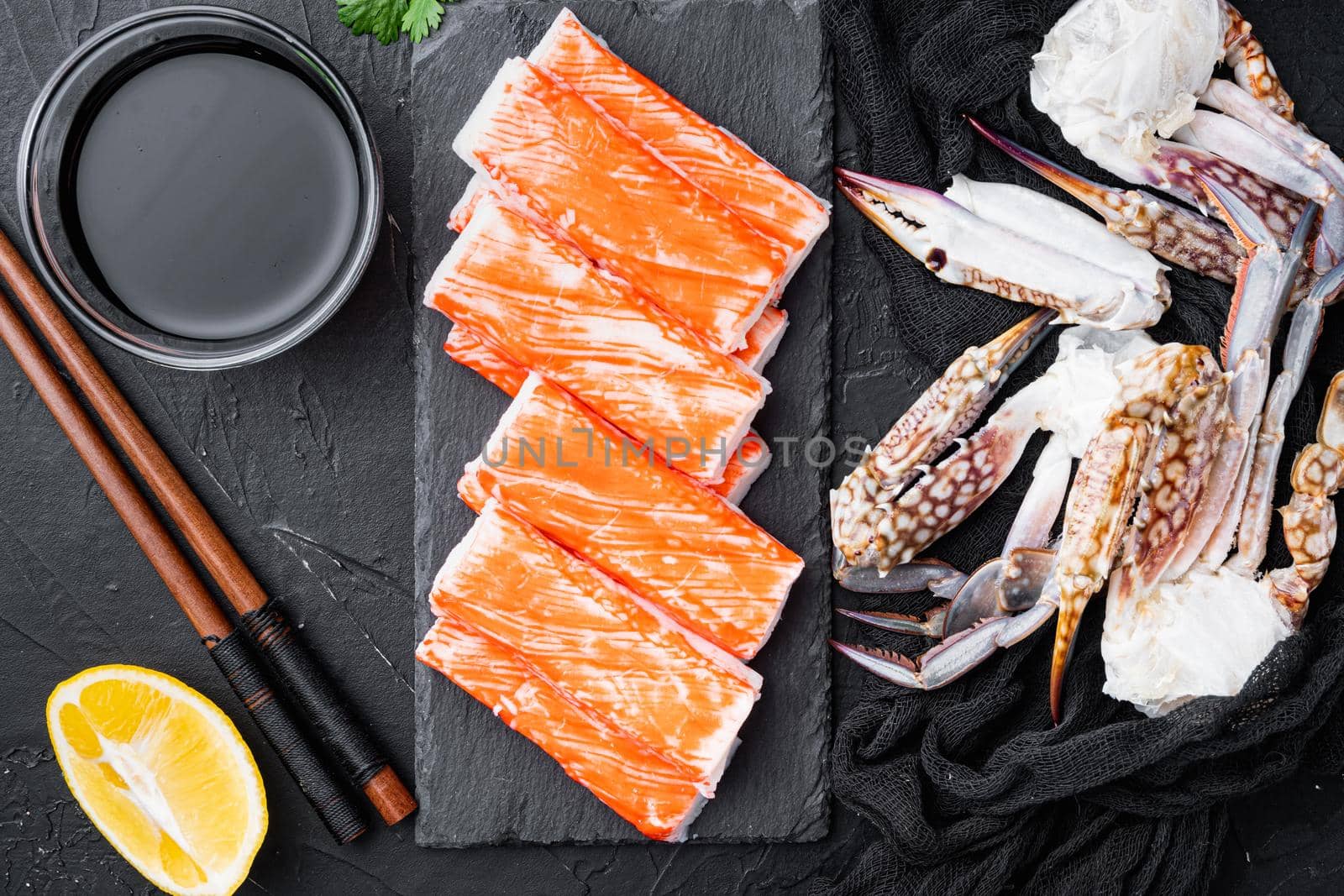Crab sticks seafood semi finished fish mince with blue swimming crab set, on stone board, on black background, top view flat lay