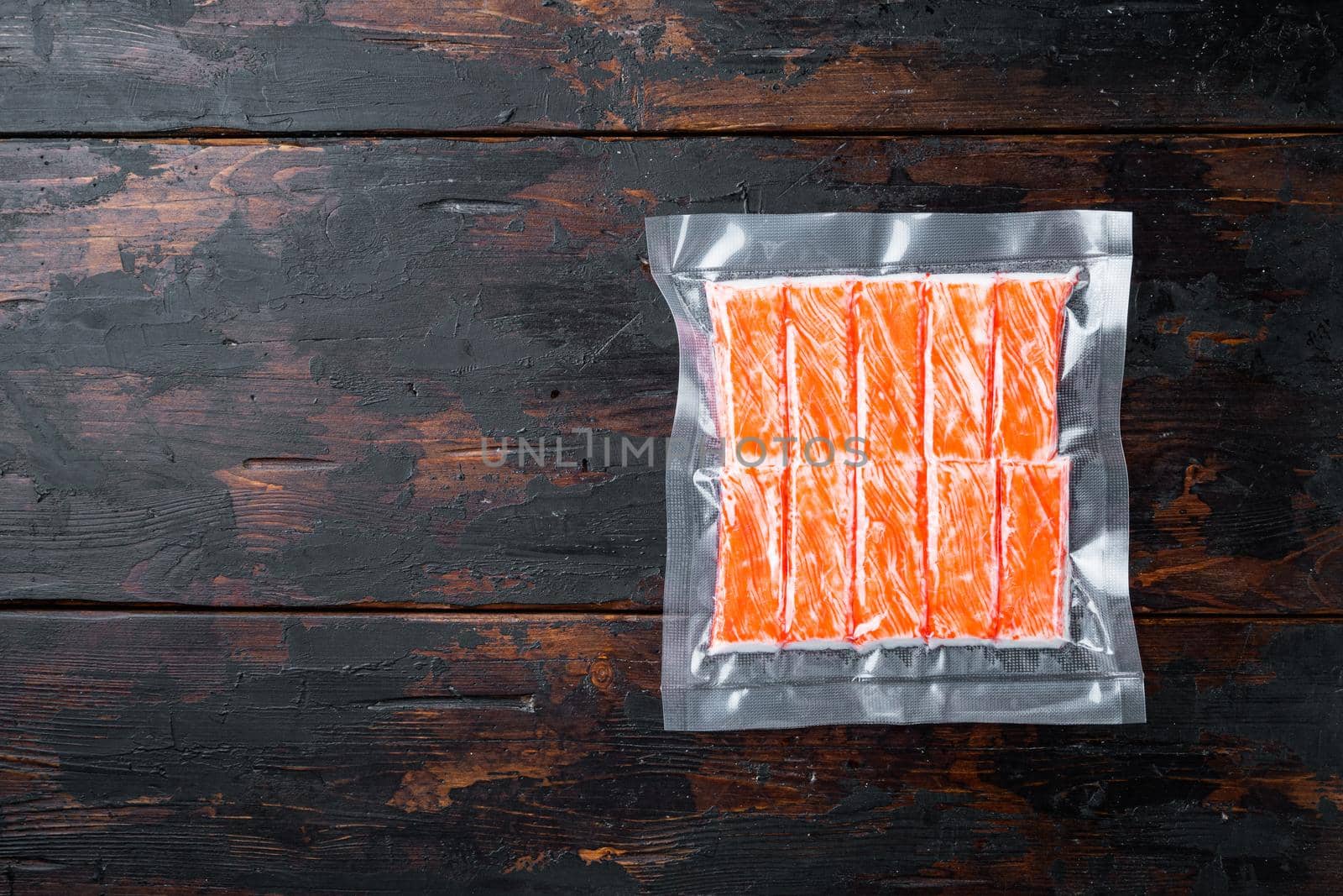 Crab stick surimi vacuum pack set, on dark wooden background, top view flat lay , with copyspace and space for text