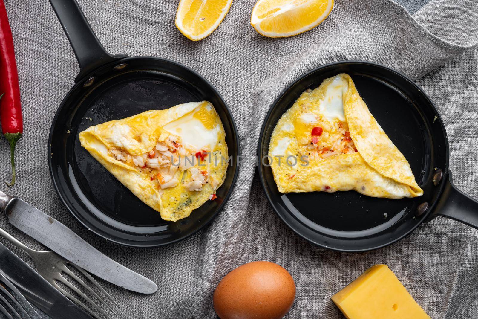 Fried breakfast omelette with a crab meat and cheese, on frying iron pan, on gray background, top view flat lay