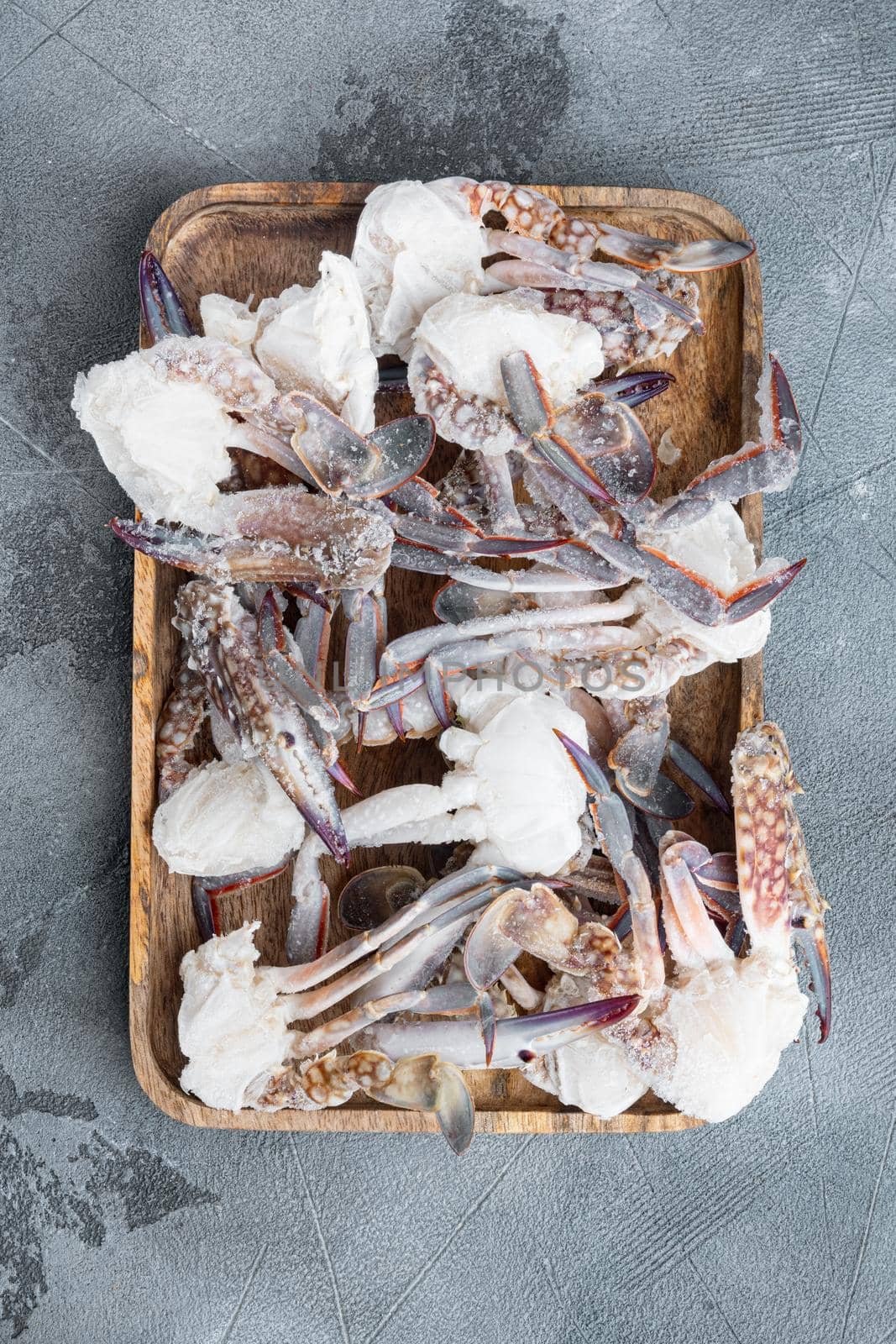 Frozen raw blue swimming crab parts set, on wooden tray, on gray background, top view flat lay