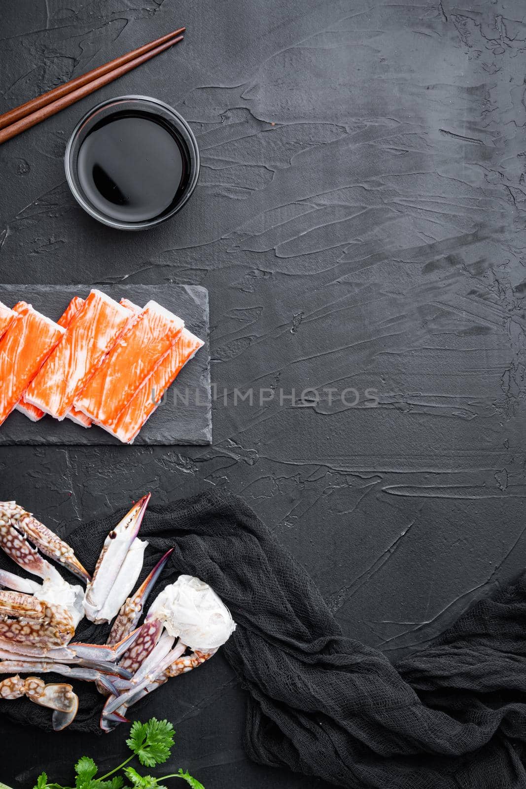 Fresh Crab meat stick surimi with blue swimming crab set, on stone board, on black background, top view flat lay , with copyspace and space for text
