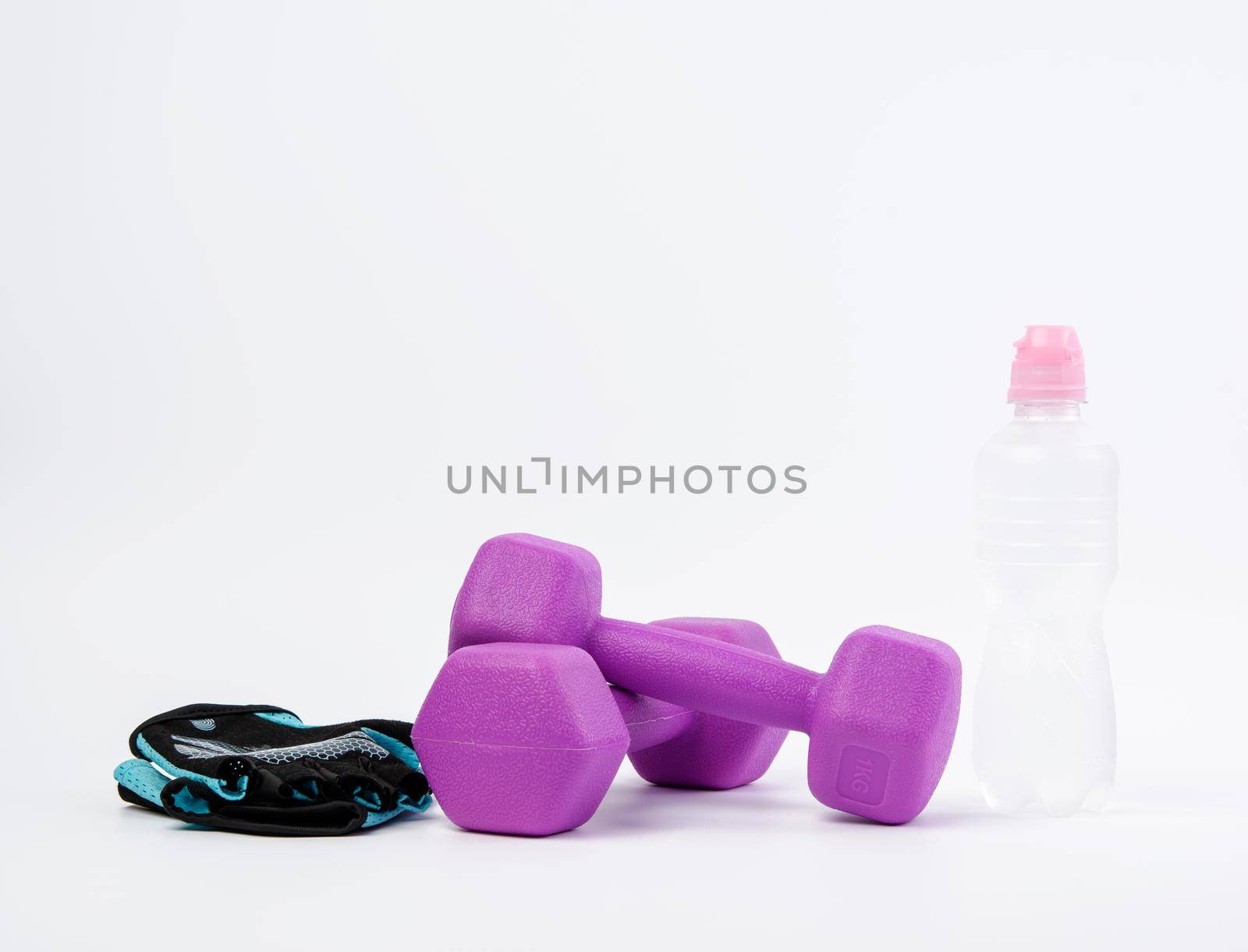 blue sports gloves, pair of purple dumbbells and and bottle of water on a white background, healthy lifestyle
