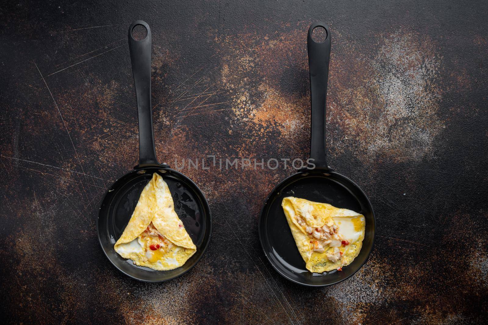 Thai Asian omelette, fresh red chilli, brown and white crabmeat, lemon, Cheddar cheese and eggs, on frying iron pan, on old dark rustic background, top view flat lay