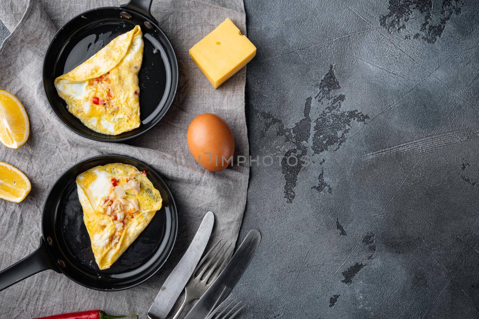 Thai Asian omelette, fresh red chilli, brown and white crabmeat, lemon, Cheddar cheese and eggs, on frying iron pan, on gray background, top view flat lay , with copyspace and space for text