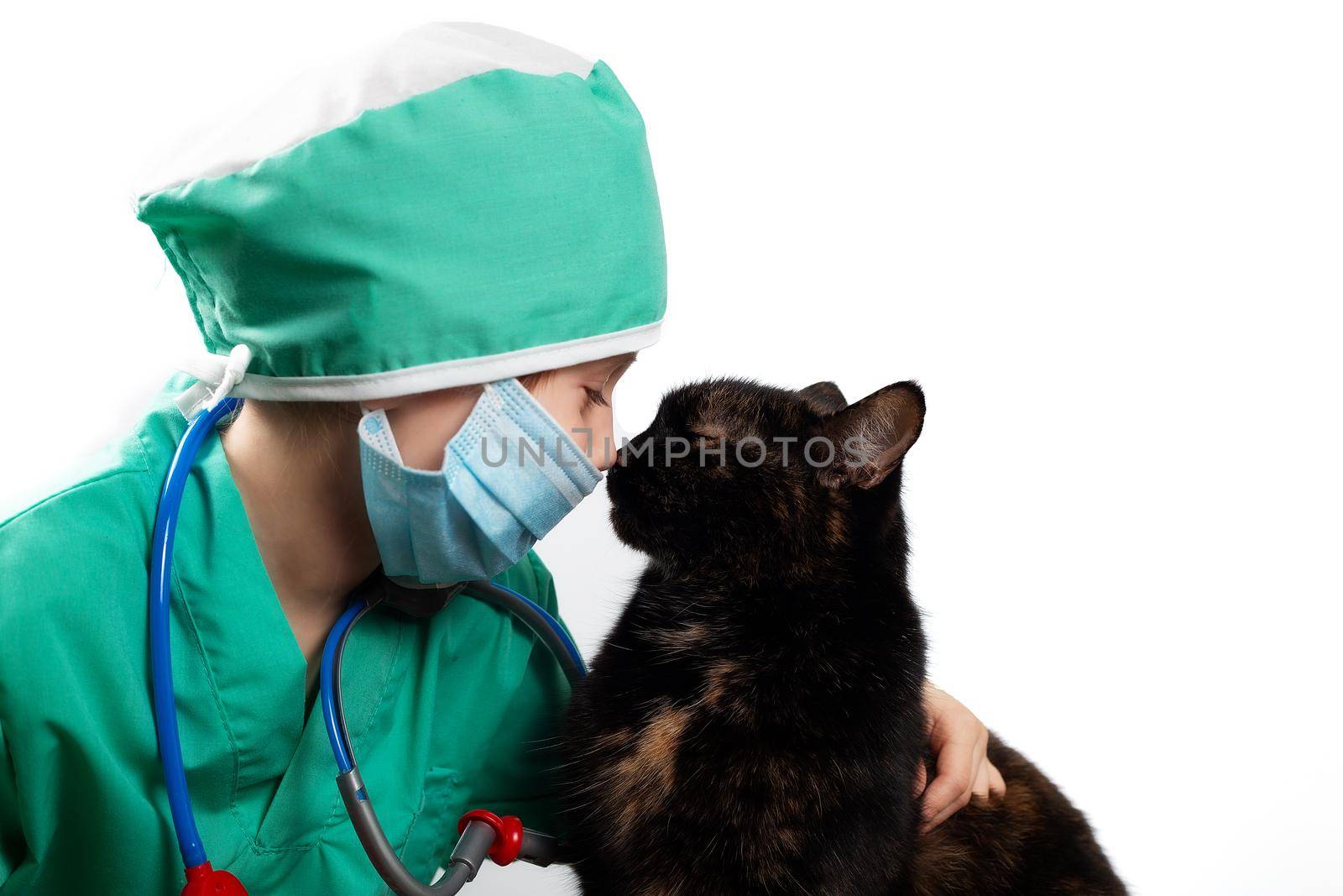 Girl in green surgical suit and medical mask plays veterinarian with cat by galinasharapova