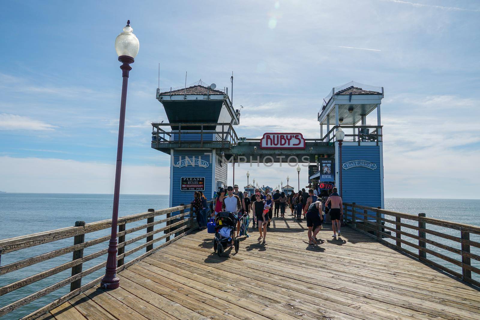 Tourist walking on the Oceanside Pier during blue summer day, Oceanside, northern San Diego County by Bonandbon