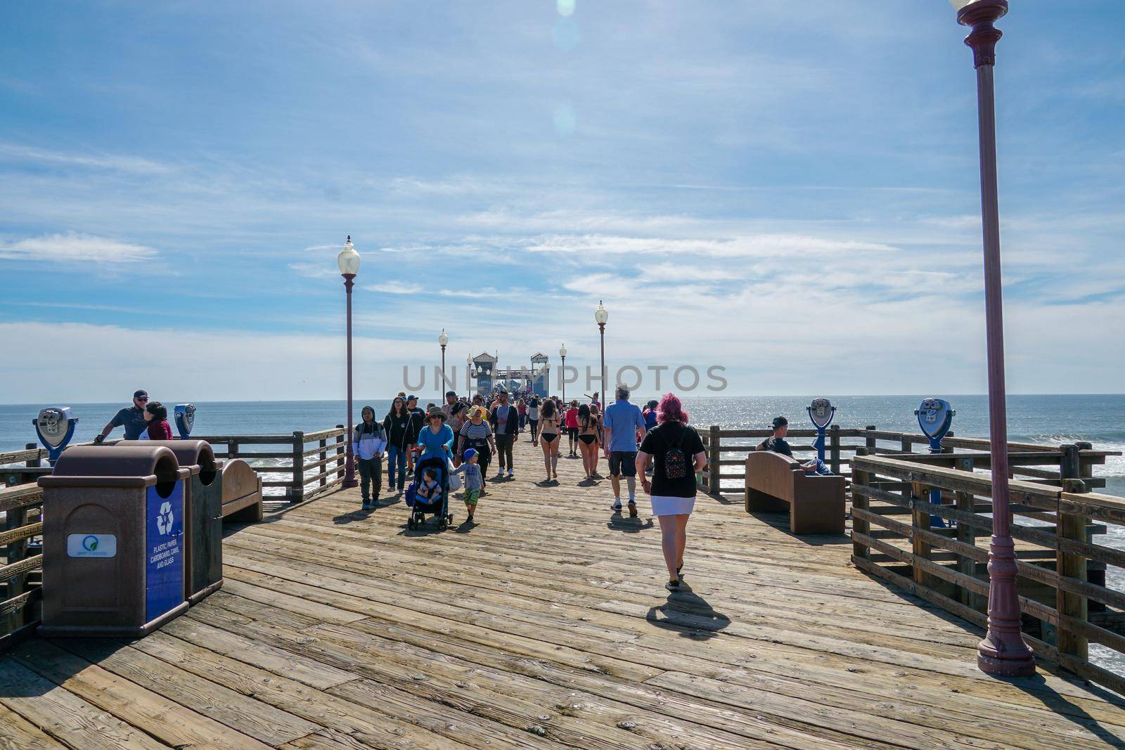 Tourist walking on the Oceanside Pier during blue summer day, Oceanside, northern San Diego County by Bonandbon