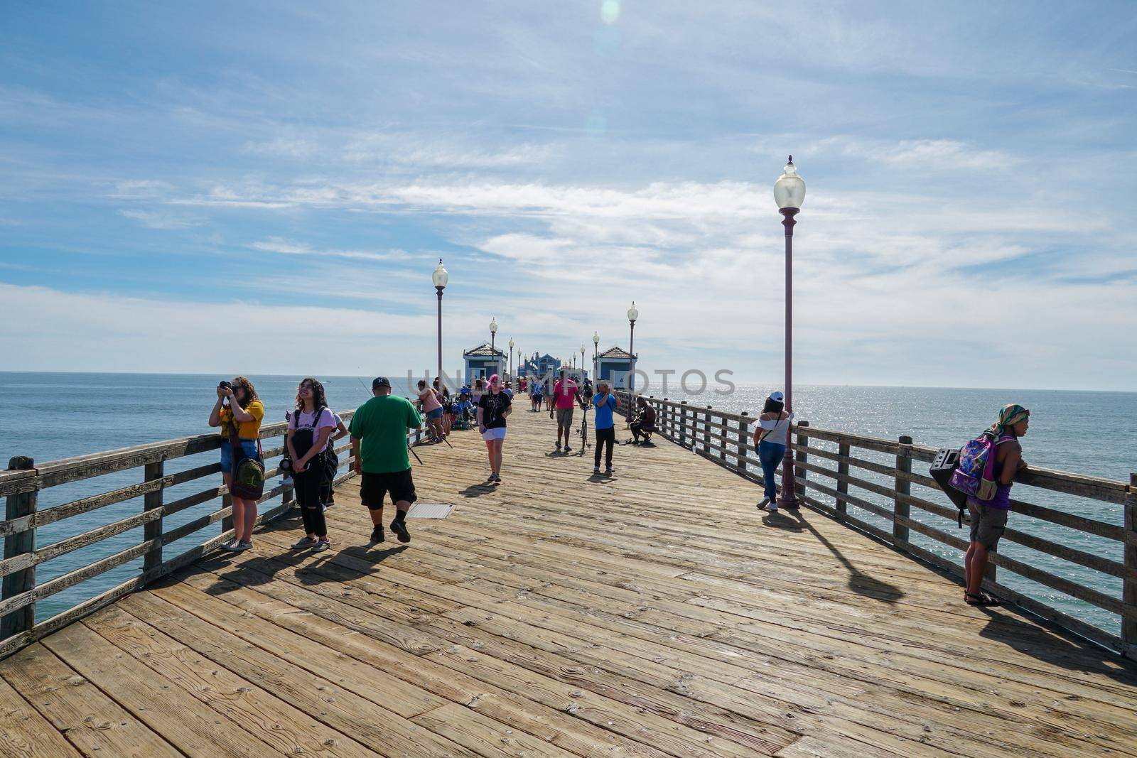 Tourist walking on the Oceanside Pier during blue summer day, Oceanside, northern San Diego, California. Wooden pier on the western United States coastline. Famous for fisher. Febraury 22n, 2020