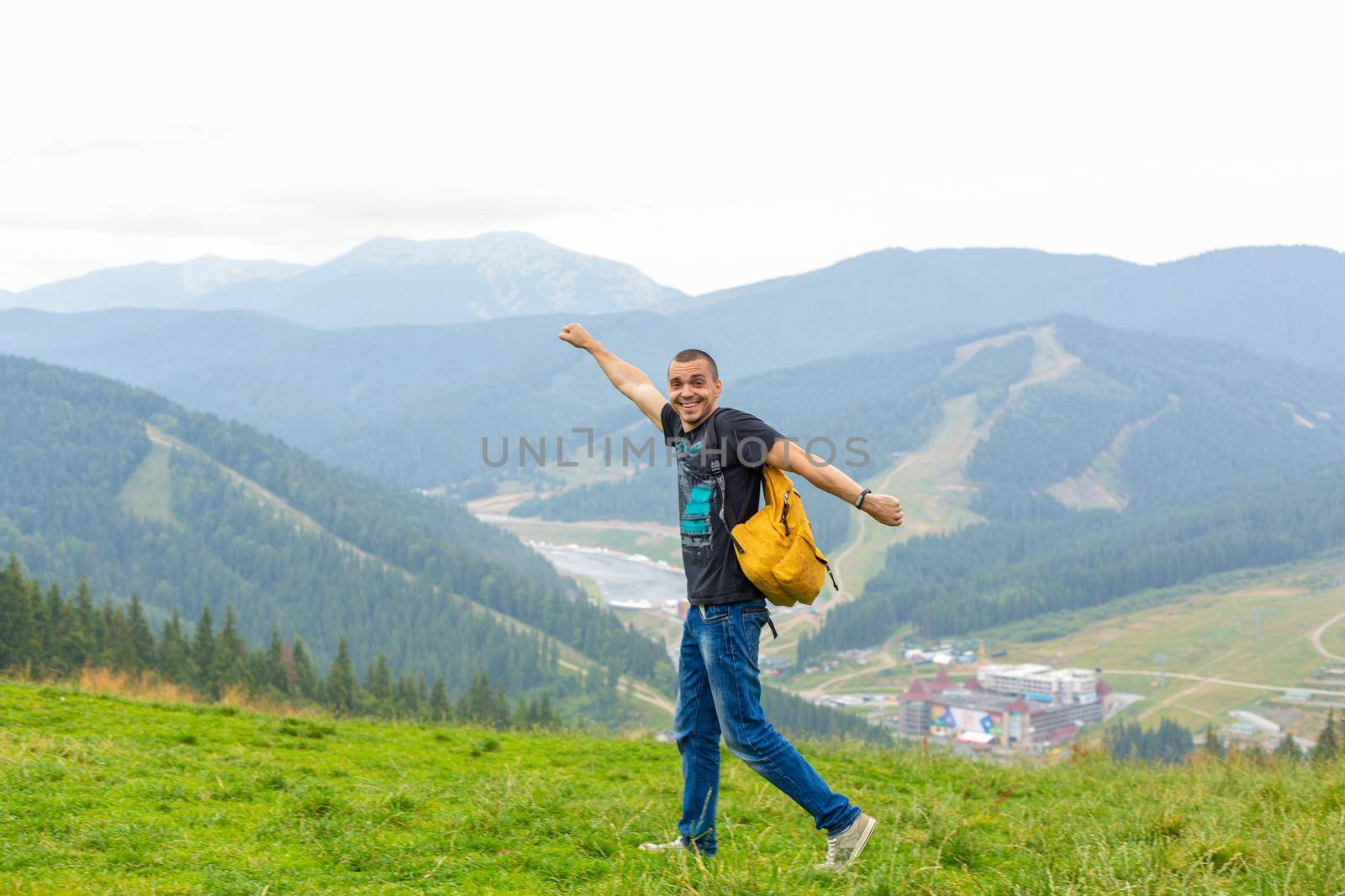 A guy travels with a yellow backpack through picturesque places with beautiful mountain landscapes.
