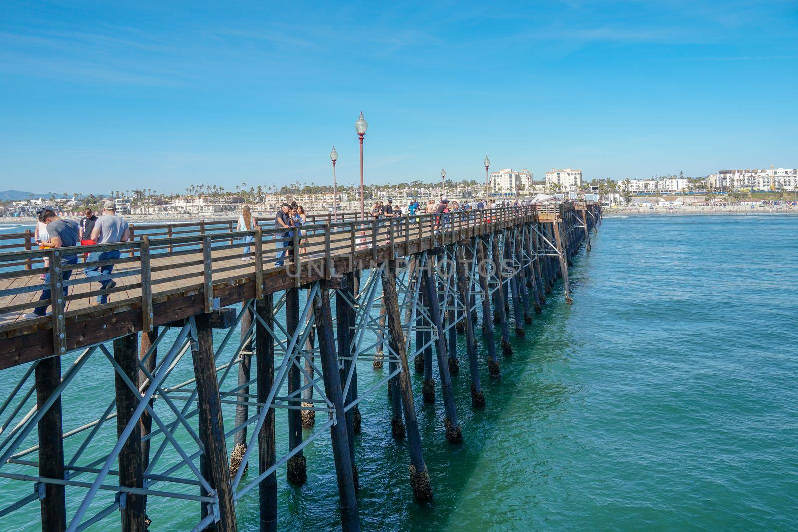 Tourist walking on the Oceanside Pier during blue summer day, Oceanside, northern San Diego, California. Wooden pier on the western United States coastline. Famous for fisher. Febraury 22n, 2020