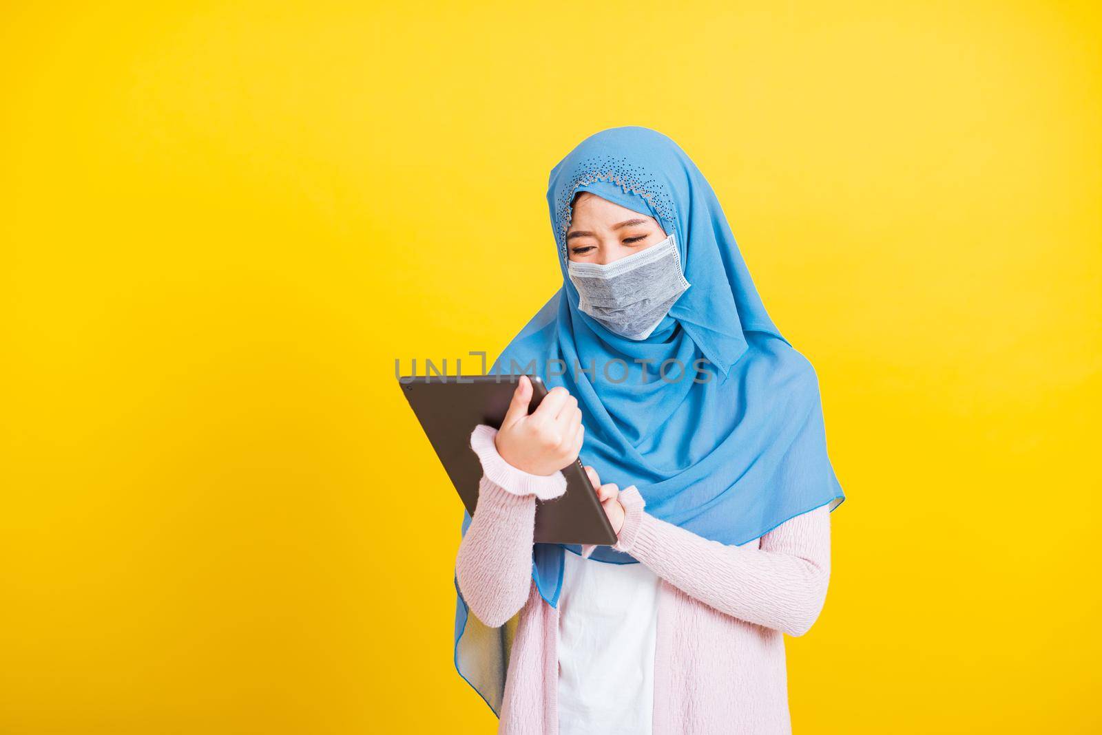 Asian Muslim Arab woman Islam wear veil hijab and face mask protect touch on tablet screen by Sorapop