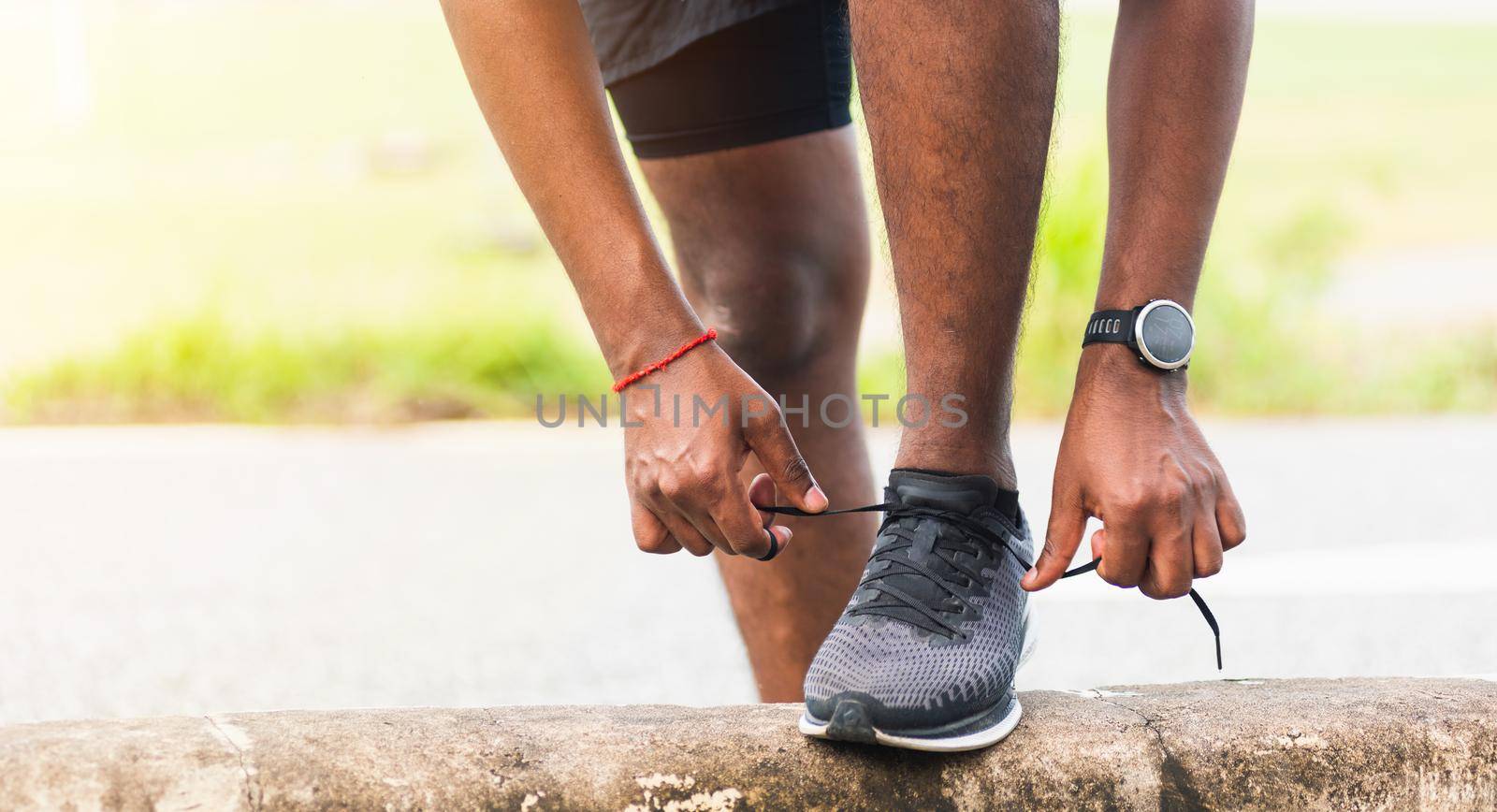 Close up Asian sport runner black man wear watch stand step on the footpath trying shoelace running shoes getting ready for jogging and run outdoor street health park, healthy exercise workout concept