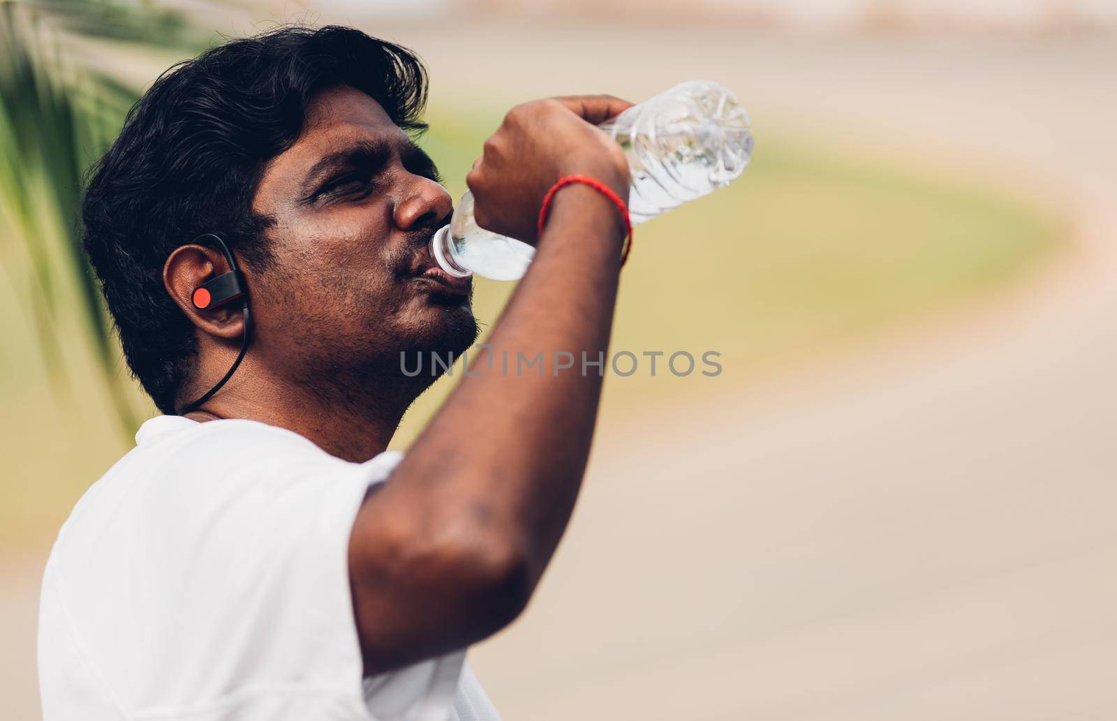 sport runner black man wear athlete headphones he drinking water from a bottle by Sorapop