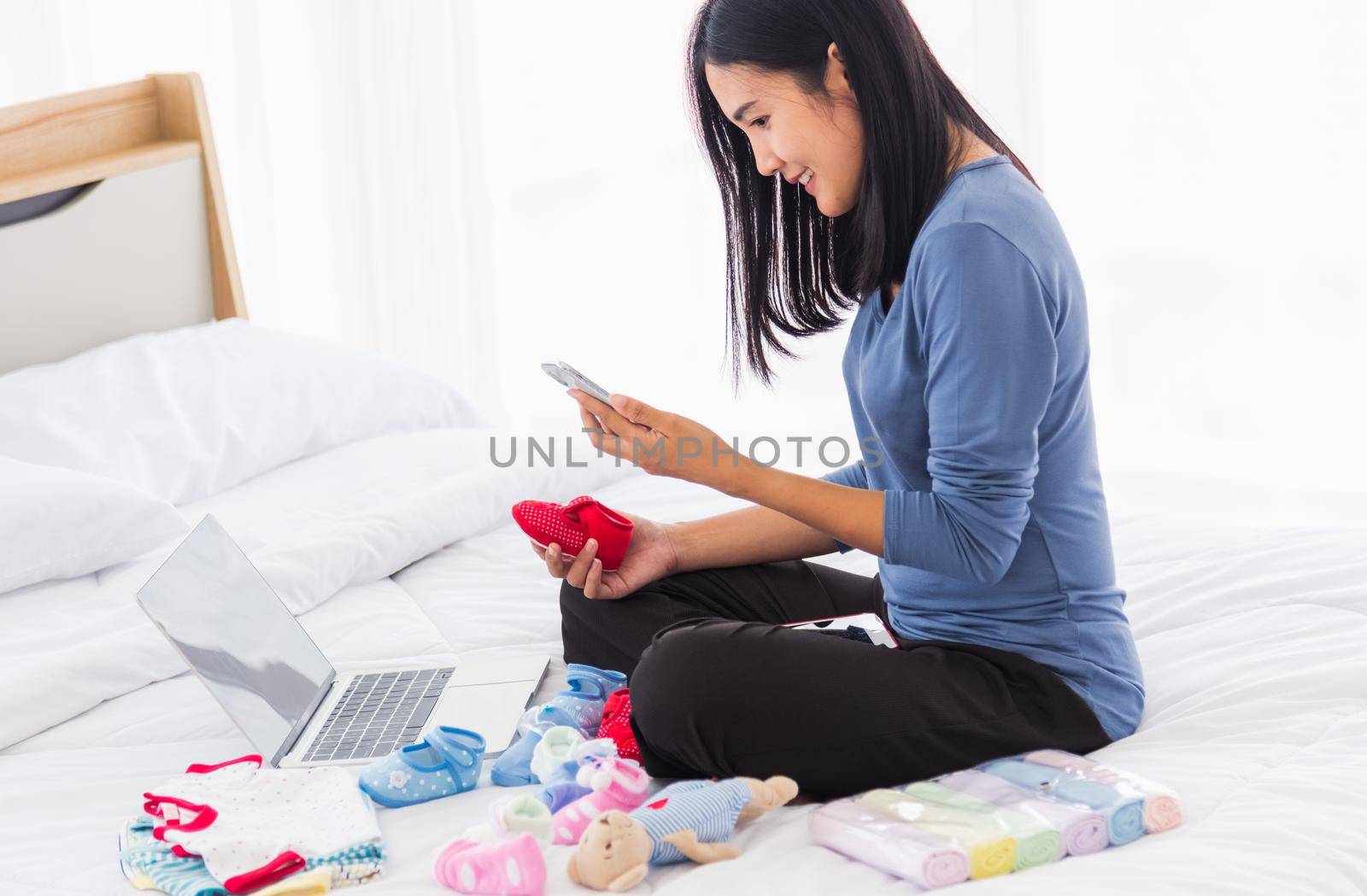 mother shopping online for her baby clothes on laptop computer by Sorapop