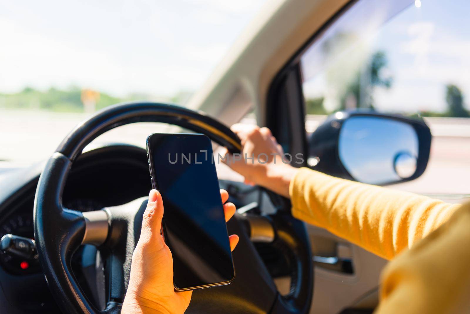 woman inside a car and using a hand holding mobile smartphone by Sorapop