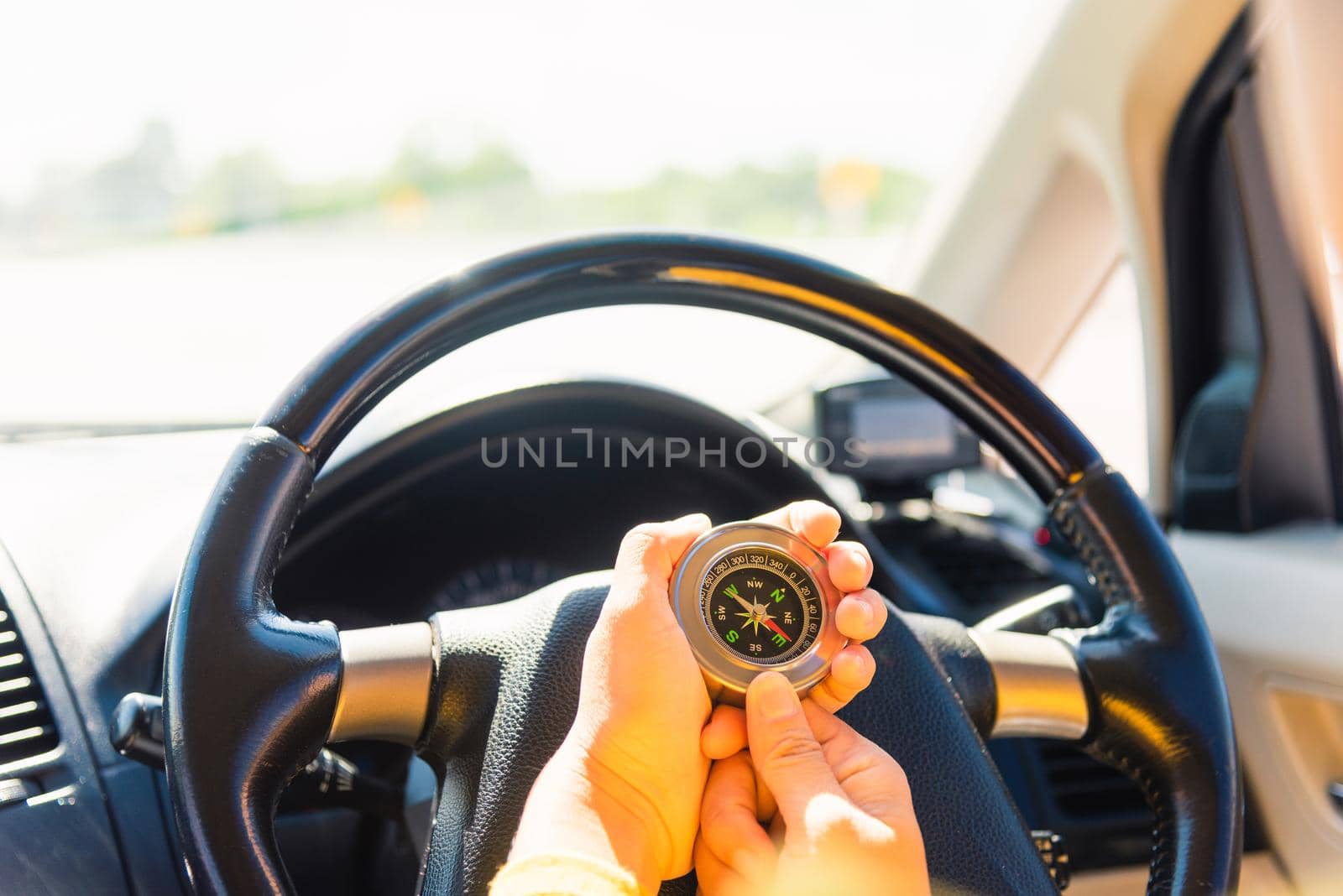 woman inside a car and using compass to navigate while driving the car by Sorapop