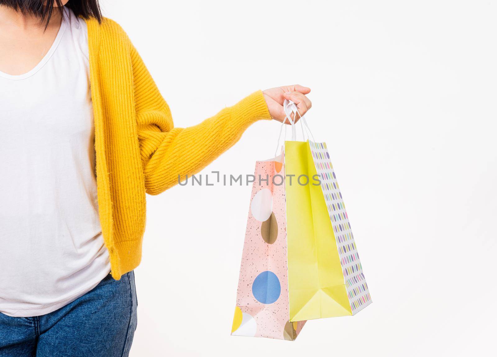 Happy young female hold many packets within arms, woman hand she wears a yellow shirt holding shopping bags multicolor isolated on white background, Black Friday sale concept