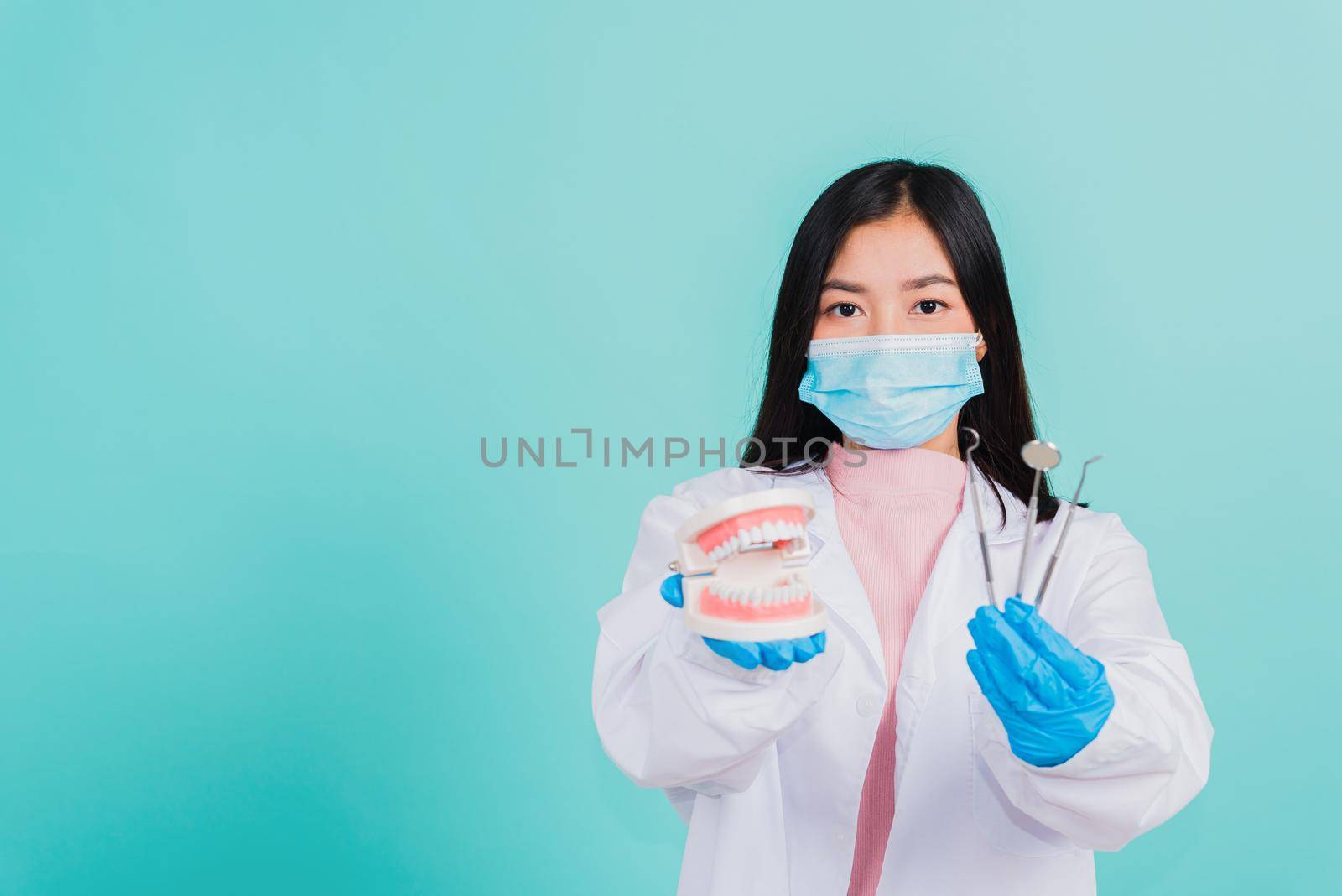 woman dentist holding professional tool and model teeth denture by Sorapop