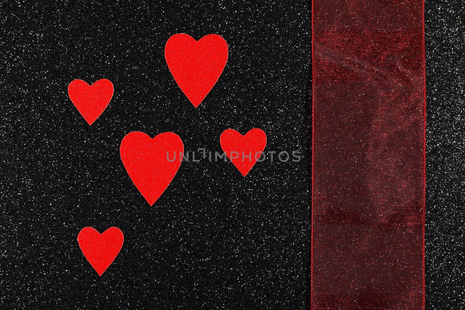 Saint Valentine's day red hearts and broad red ribbon design on textured black background