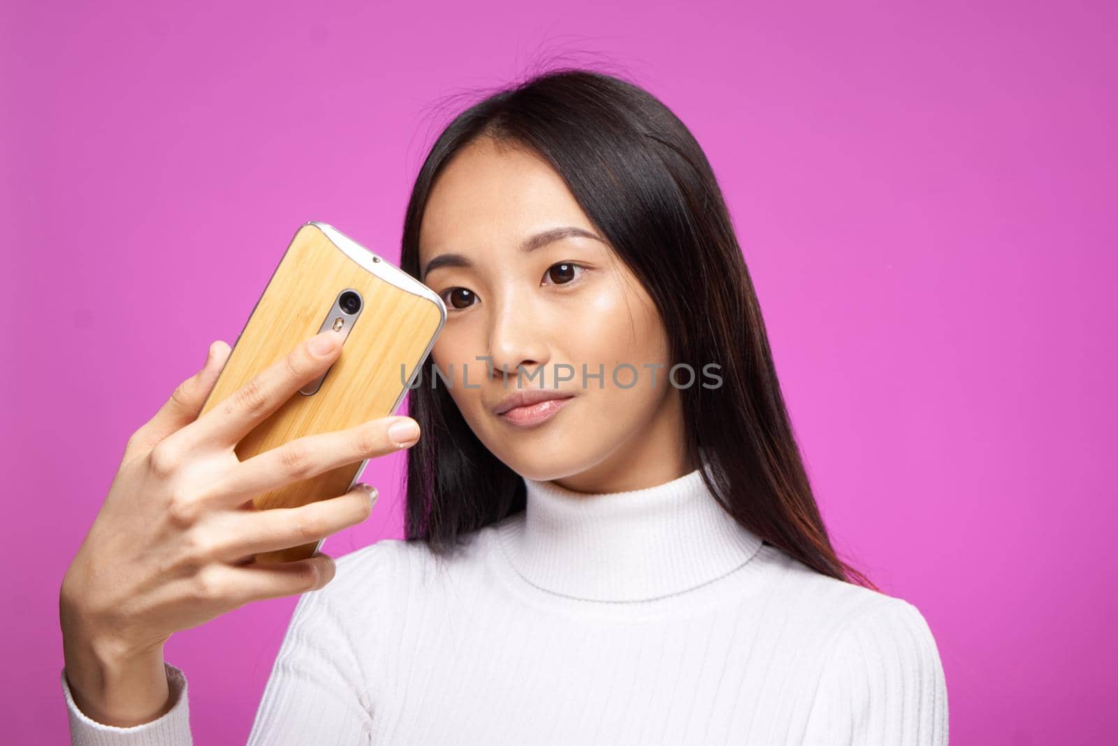 cute asian appearance phone in hand internet communication technology pink background. High quality photo