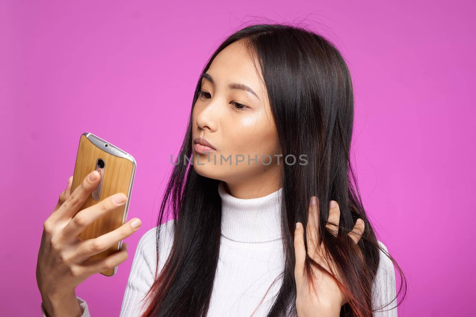 cheerful pretty brunette with a phone in her hands communication internet technology pink background by SHOTPRIME