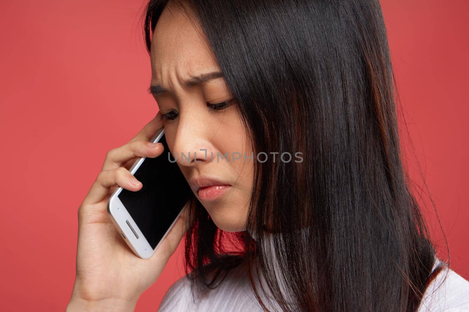 woman of asian appearance and contented facial expression talking on the phone close-up red fund by SHOTPRIME