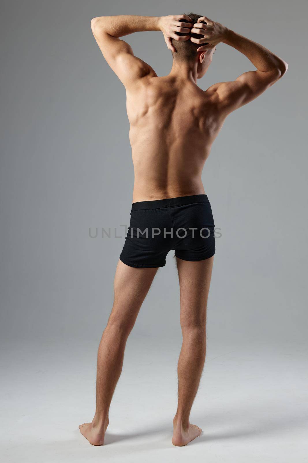 sporty man in black shorts holds hand on head back view workout fitness. High quality photo