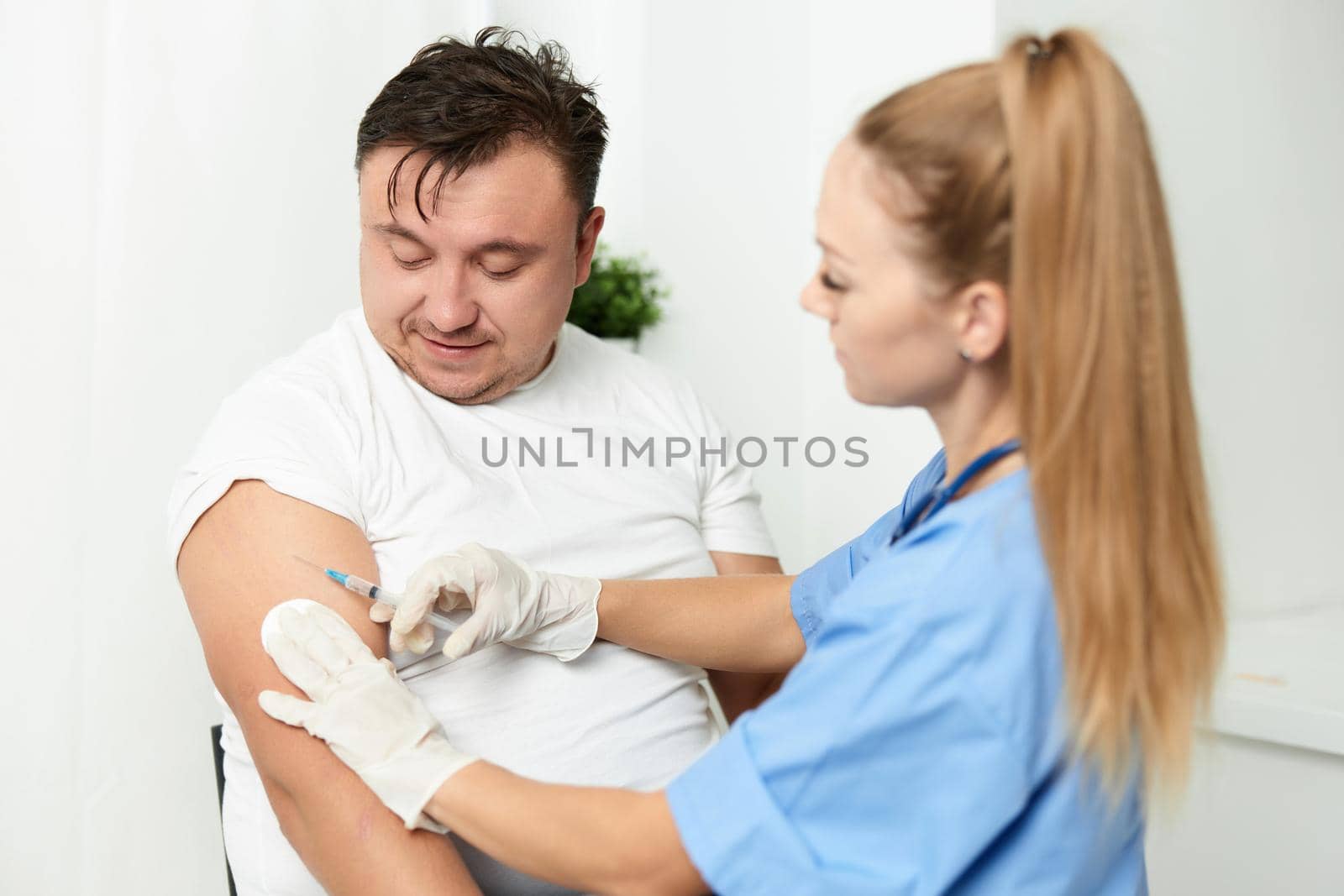 female doctor injects the vaccine into the arm of a male patient by SHOTPRIME