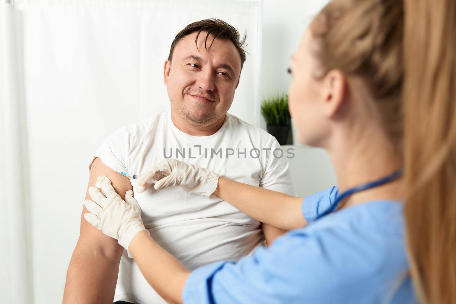 woman doctor injections in the shoulder of a man patient health care. High quality photo