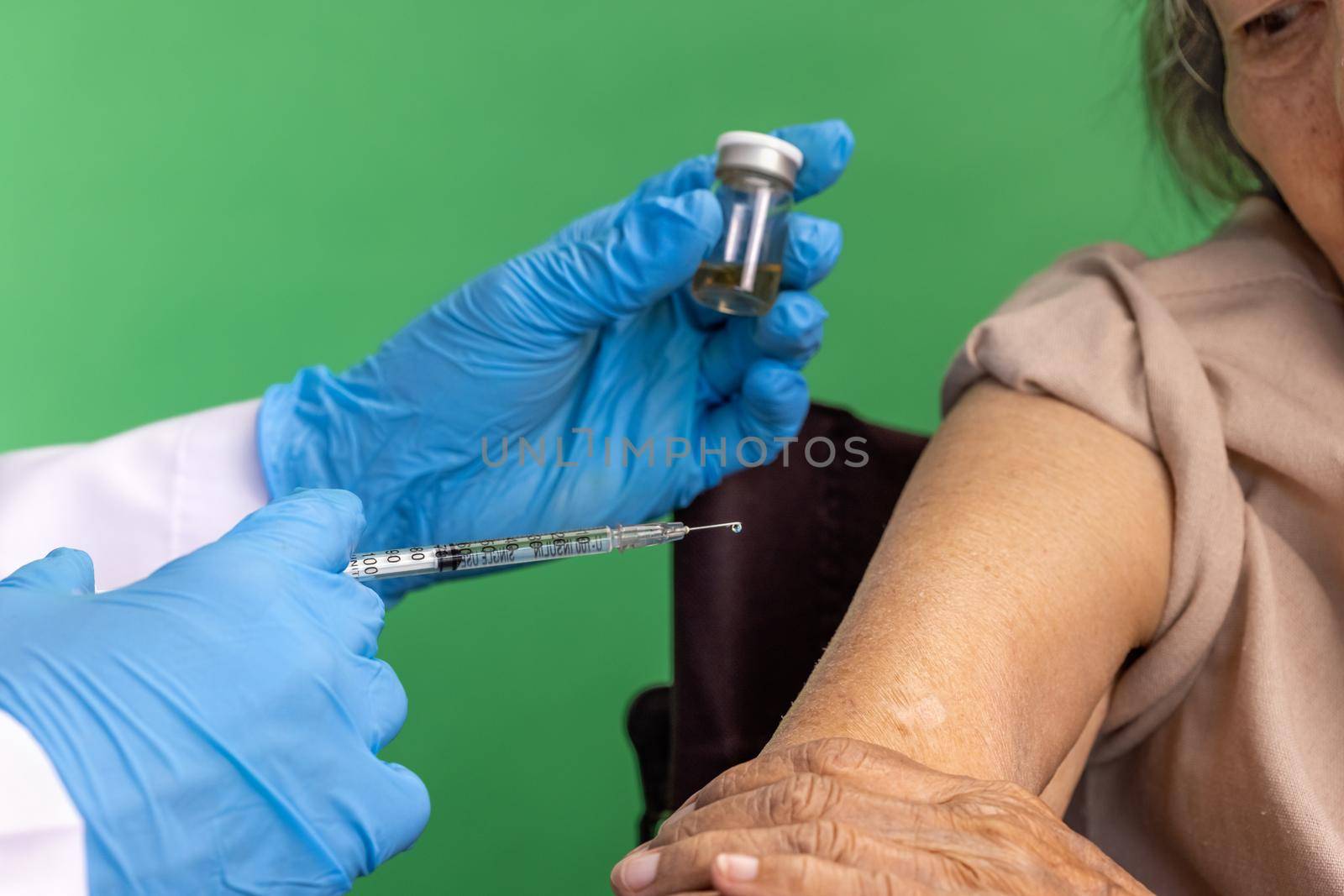 Chroma key, nurse doing vaccine injection to senior woman.