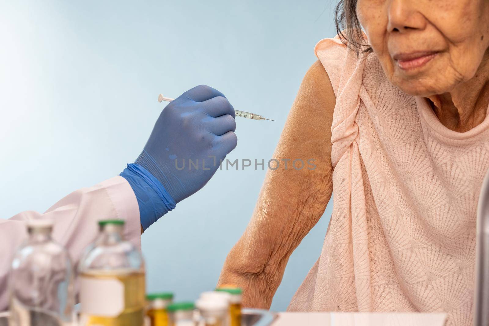 Doctor doing vaccine injection to senior woman.