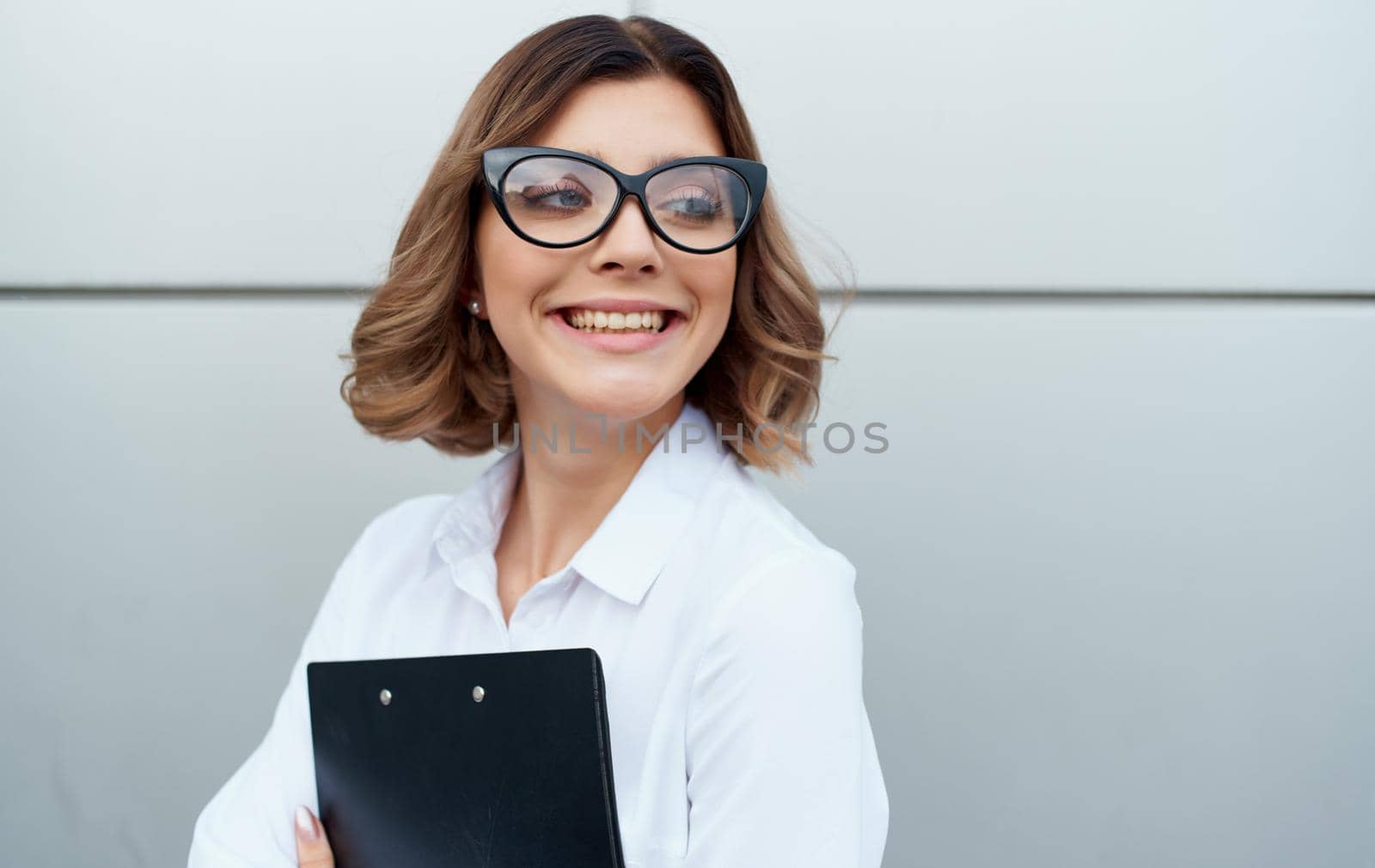 happy businesswoman near building with documents in hands and glasses on face cropped view by SHOTPRIME