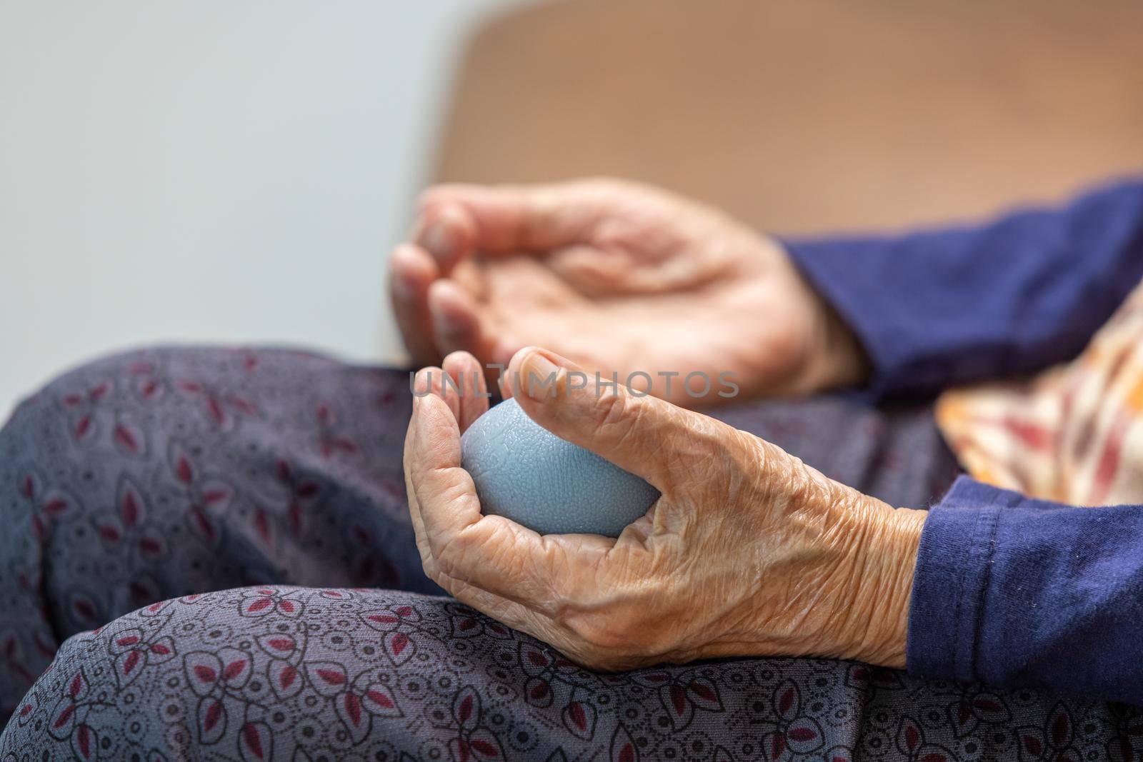 Elderly woman doing rubber ball for exercise fingers, palm ,hand and foot muscle with caregiver take care. by toa55