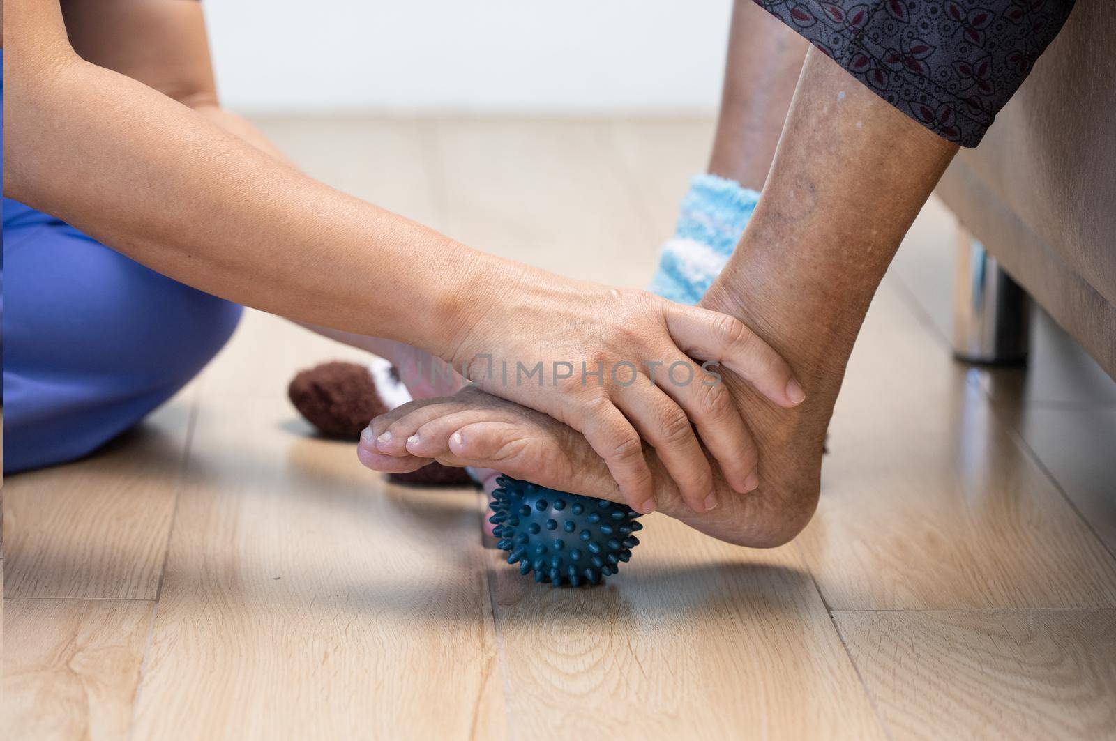 Elderly woman doing rubber ball for exercise fingers, palm ,hand and foot muscle with caregiver take care.