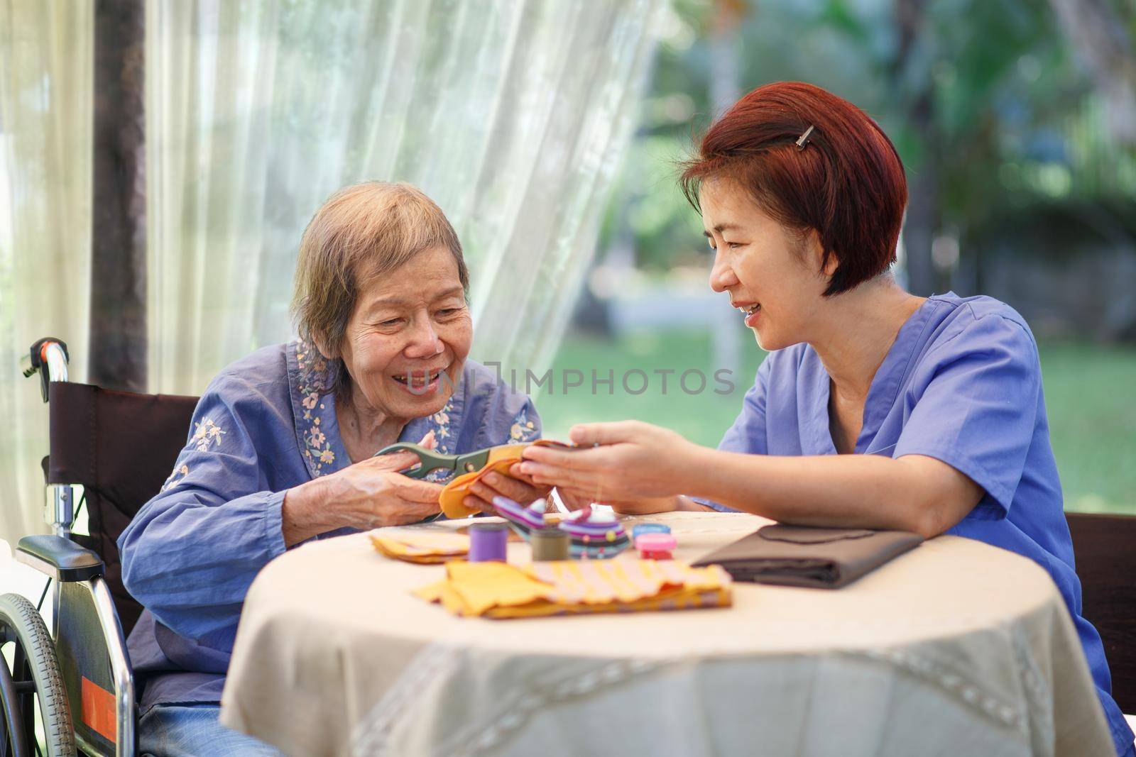 Elderly woman with caregiver in the needle crafts occupational therapy  for Alzheimer’s or dementia